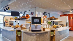 Un bar à petit-déjeuner moderne, doté d’un écran numérique, proposant une variété de viennoiseries et un ballon de basket.