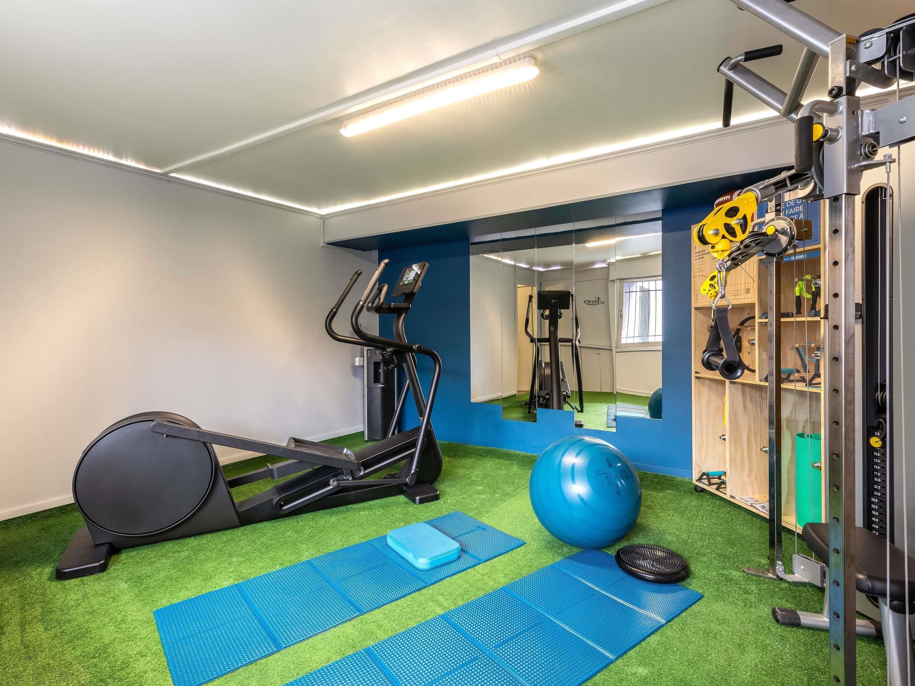 A gym with exercise equipment, a blue exercise ball, and a treadmill.