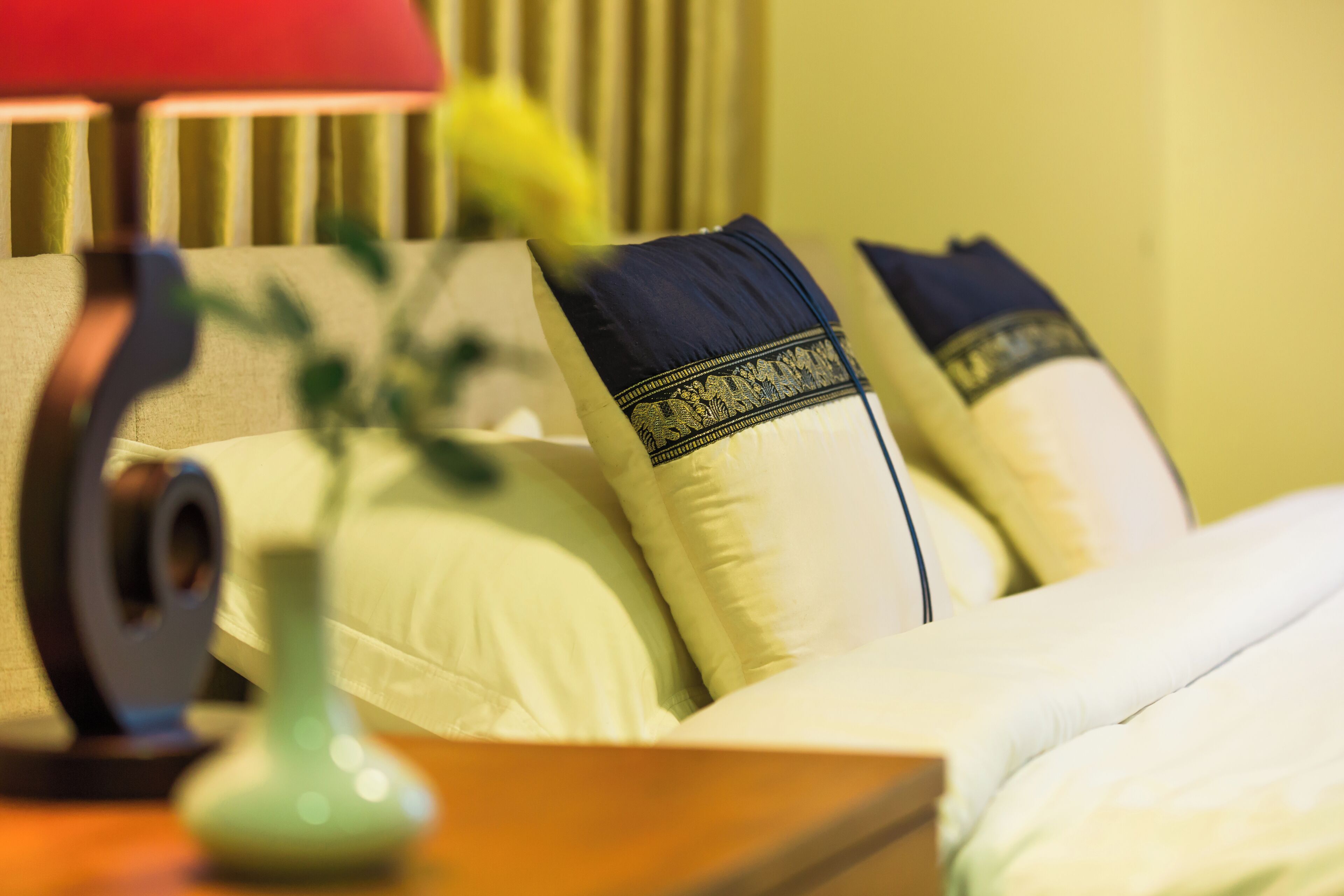 A neatly made bed with white bedding and decorative pillows.