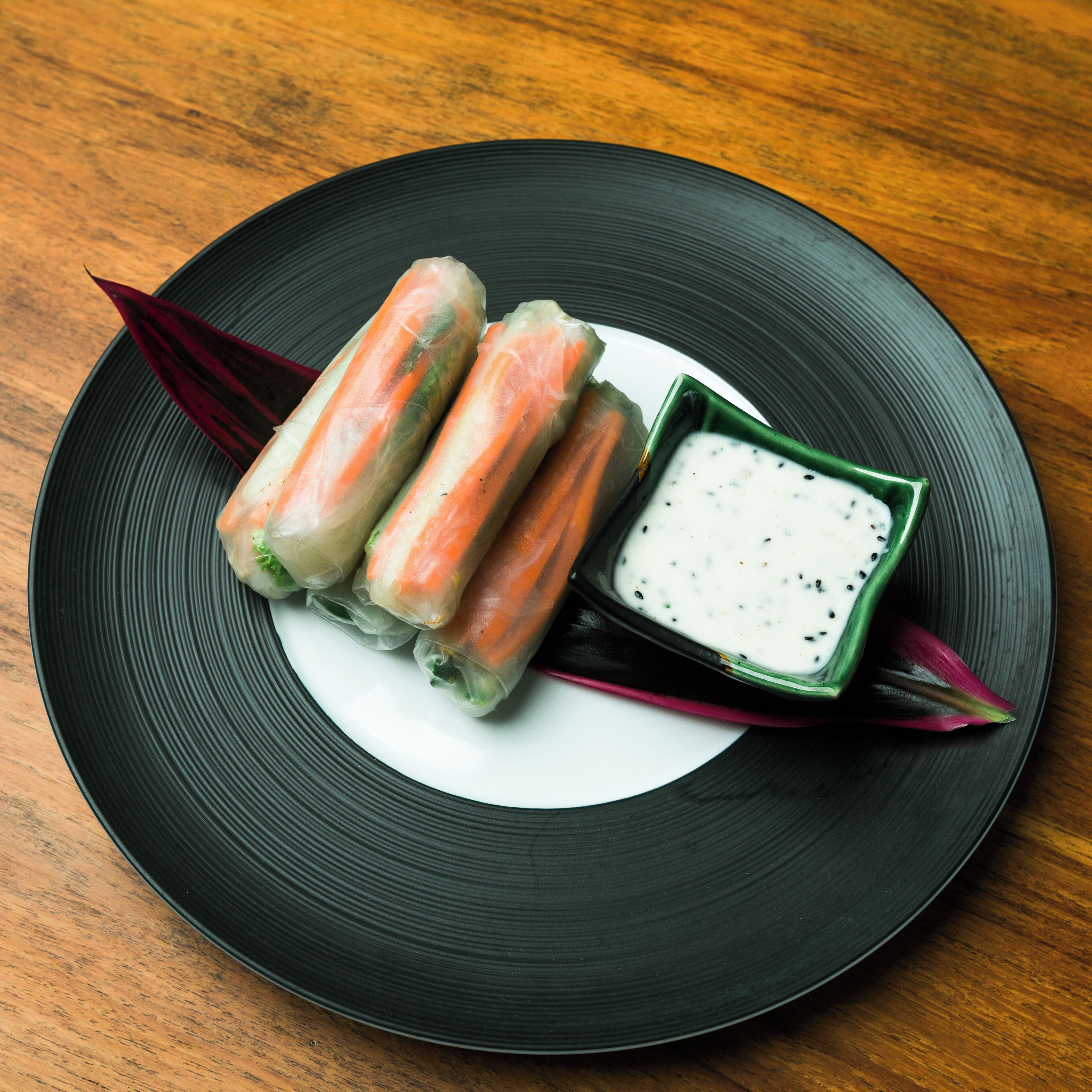 Un plat de rolls de primavera amb una salsa per acompanyar.