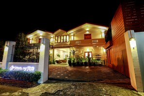 A hotel entrance with a sign reading "Ambassador Hill," a paved driveway, and a gated entrance. - Ambassador Hill (Yangon)