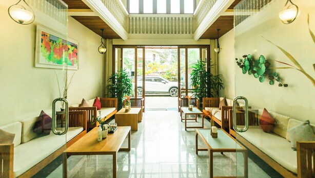 Un vestíbulo espacioso con techo alto, mobiliario de madera y ventanas amplias que ofrecen vistas al exterior.