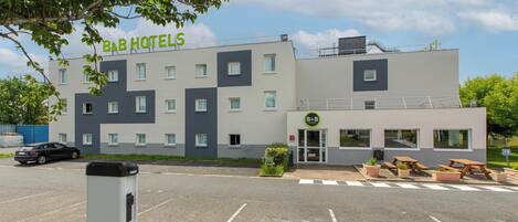 A B&B hotel with a modern design, a parking lot, and outdoor seating.
