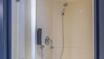 A shower with a handheld showerhead and a wall-mounted faucet.