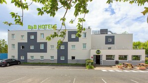 A B&B hotel with a modern design, featuring a parking lot and outdoor seating area. - B&B HOTEL Châteauroux A20 L'Occitane (Deols)