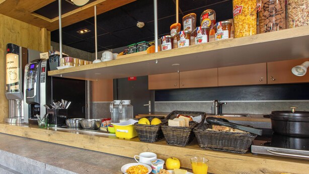 A breakfast buffet with various food items, baskets, and kitchen equipment. - B&B HOTEL Châteauroux A20 L'Occitane (Deols)