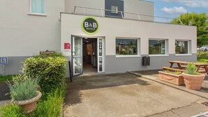 A B&B hotel with a reception area, a patio with a table and chairs, and potted plants. - B&B HOTEL Châteauroux A20 L'Occitane (Deols)