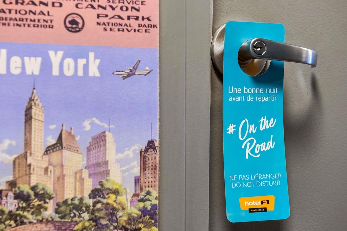 A hotel room door with a blue hotelF1 tag and a poster of New York City.