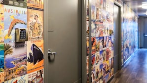A hallway with travel posters on the walls and a door with a keypad lock. - hotelF1 Roissy CDG (Roissy-en-France)