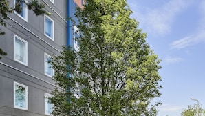 A hotel with a modern facade, a landscaped garden with a pond, and a clear blue sky. - hotelF1 Roissy CDG (Roissy-en-France)