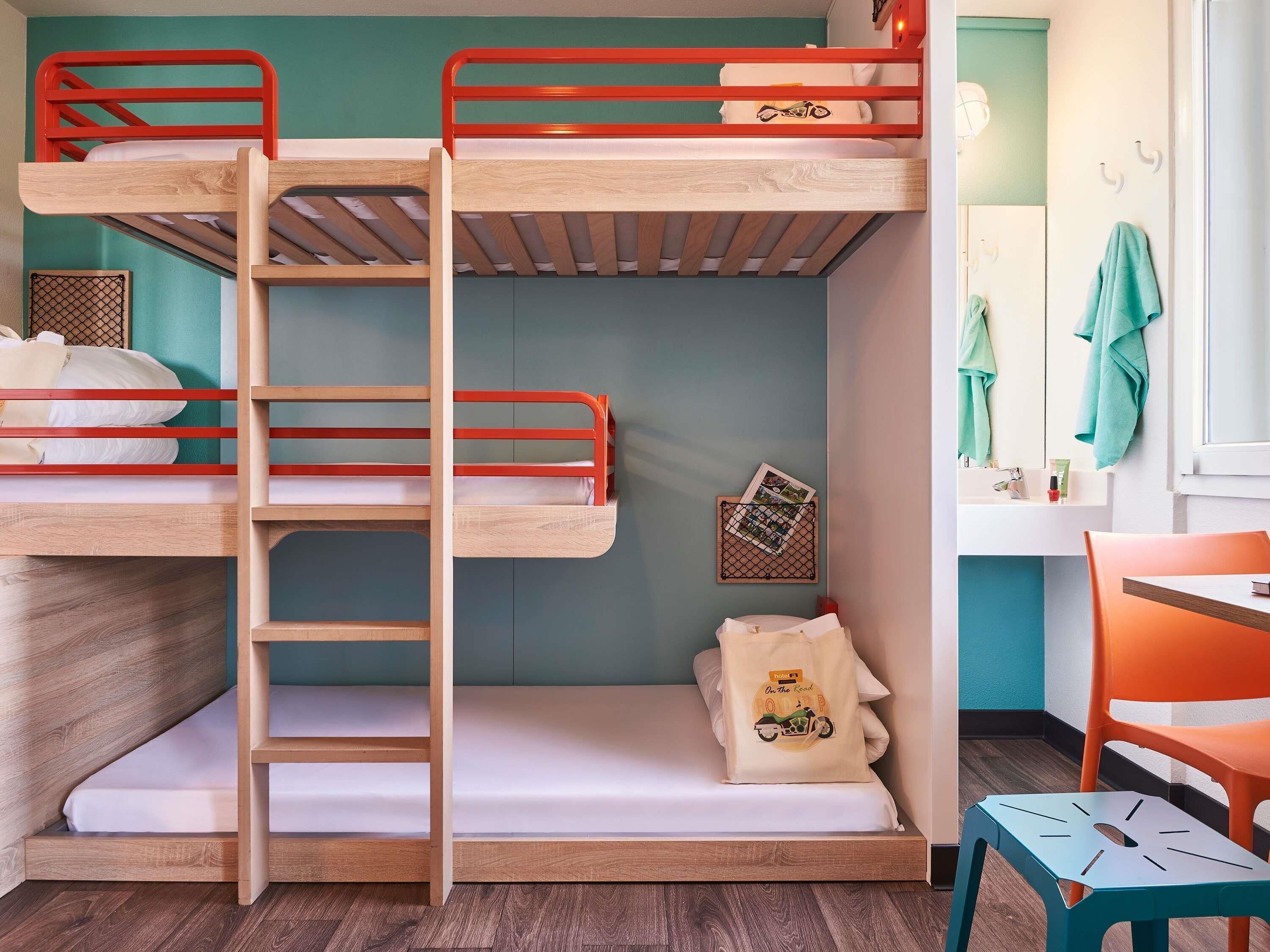 A bunk bed room with a desk and chair, a small shelf, and a wall-mounted picture.