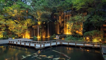A serene pond with koi fish, surrounded by lush greenery and a wooden deck.