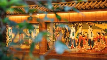 A traditional Japanese interior with a wooden ceiling and a large mural depicting historical figures.