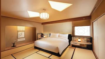 A hotel room with a large bed, bedside tables with lamps, a wall-mounted artwork, and tatami flooring.
