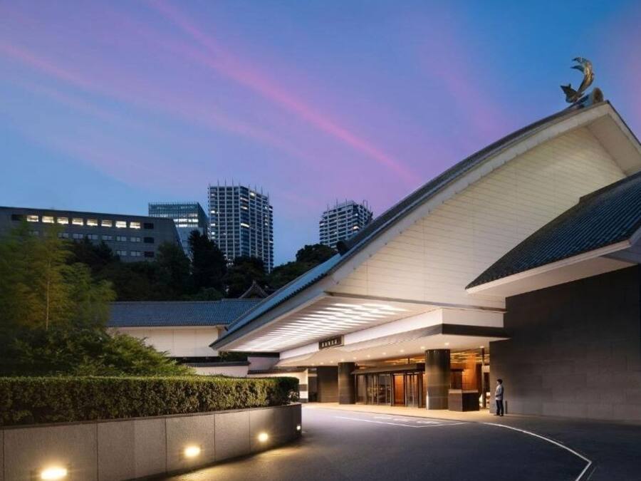 Un edificio moderno con techo curvo y una persona cerca de la entrada.