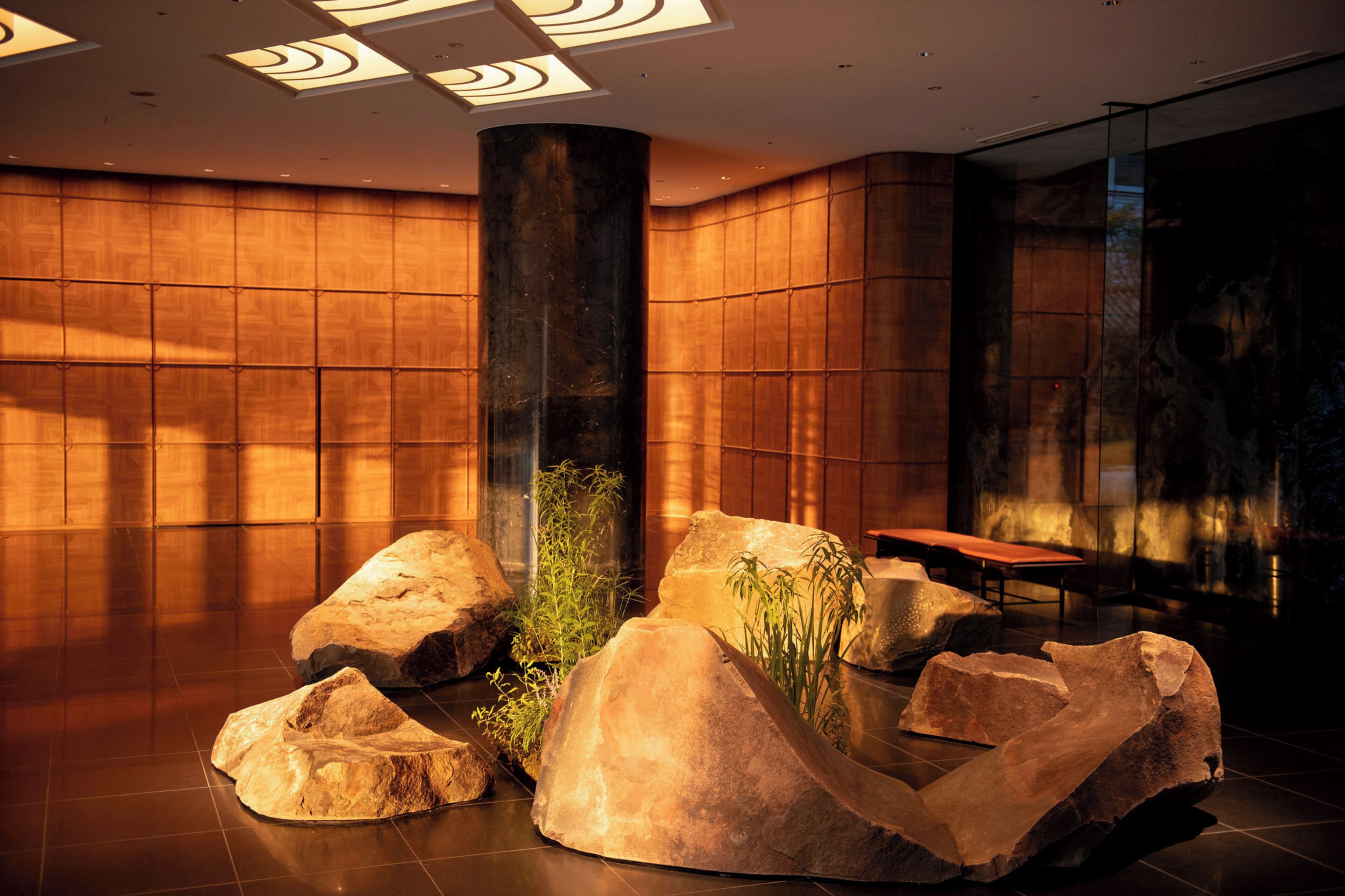 Eine moderne Lobby mit einer zentralen Säule, großen Felsen und einer Sitzgruppe.
