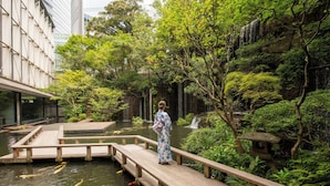 A traditional Japanese garden with a wooden bridge, koi fish pond, and lush greenery.