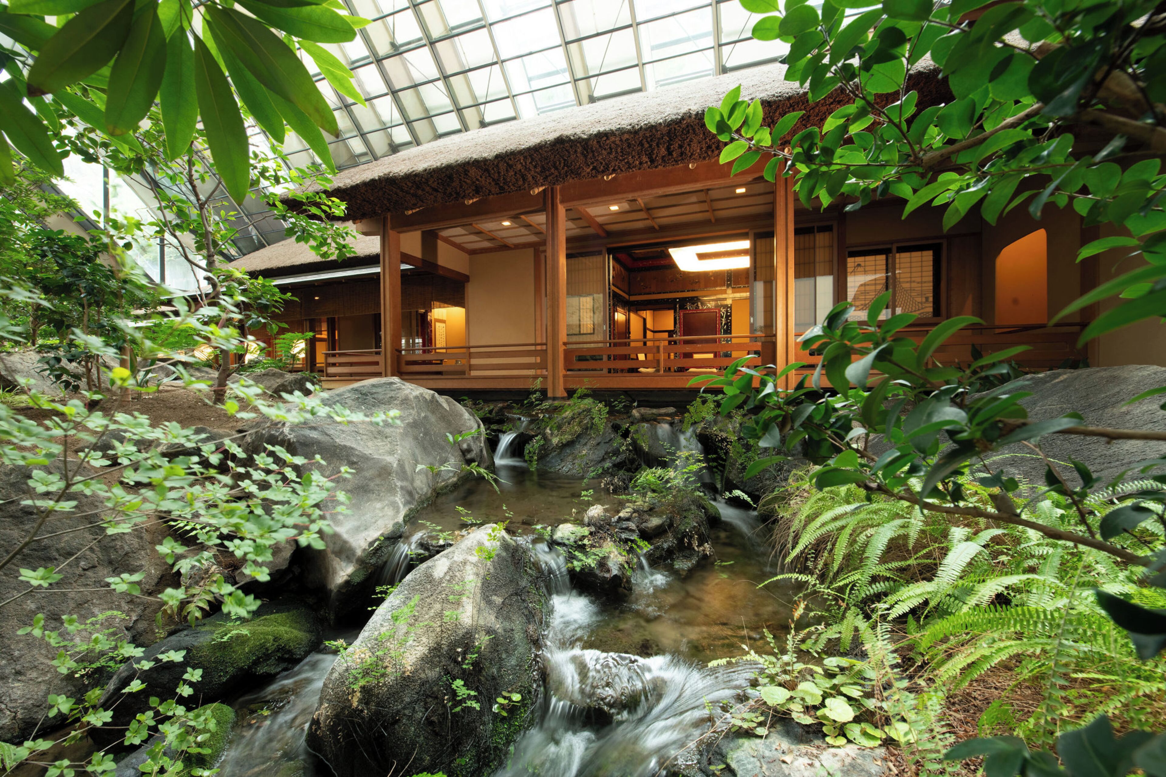 Il s’agit d’un bâtiment de style japonais traditionnel, avec une façade en bois et un toit de chaume, entouré d’un jardin de rochers naturel et d’un petit ruisseau.