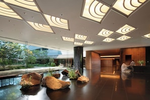 A modern lobby with a glass wall, large rocks, and a reception desk.
