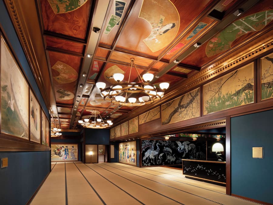 Um interior japonês tradicional com tatames, vigas de madeira e obras de arte nas paredes.