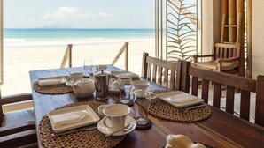 A wooden table set for dining with a view of the beach. - Clef des Iles (Mahé Island)