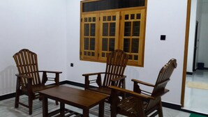 Une pièce avec une table en bois et quatre chaises en bois, une fenêtre avec des volets en bois et un mur blanc.
