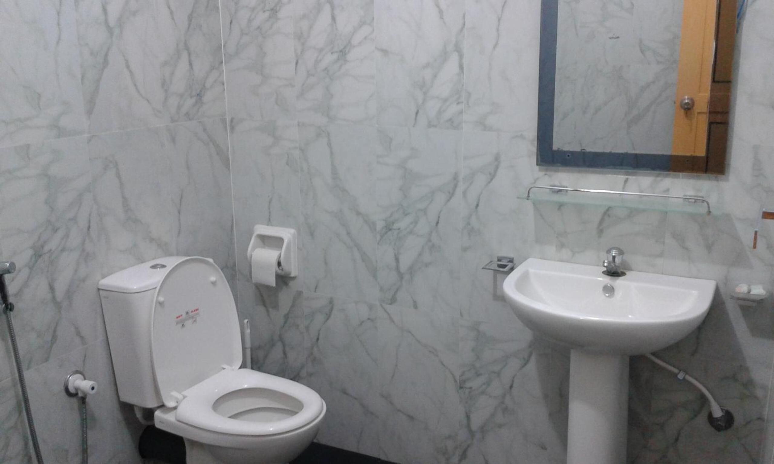 A bathroom with a toilet, a sink, and a mirror.