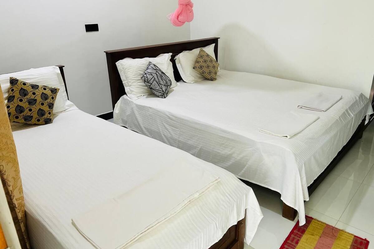 Una habitación con dos camas, cada una con sábanas blancas y almohadas estampadas.