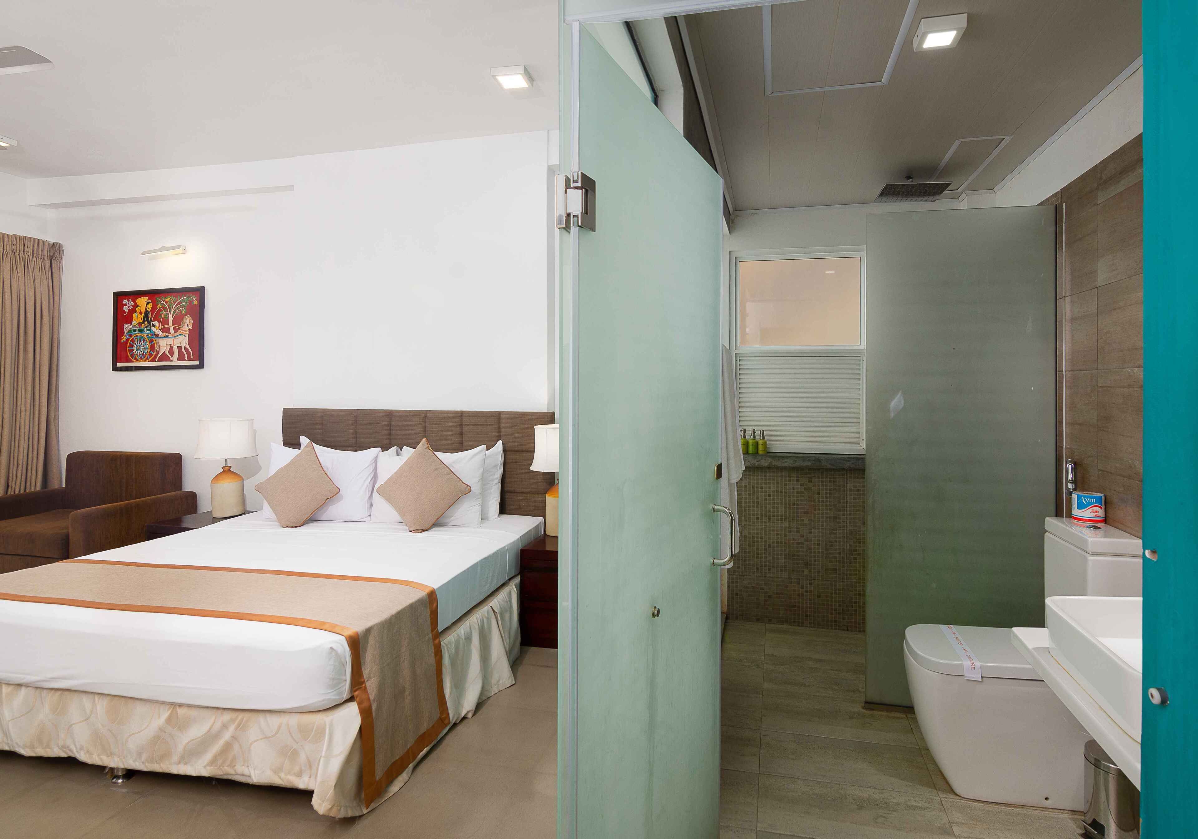 A hotel room with a bed, bedside table, lamp, and a painting on the wall.