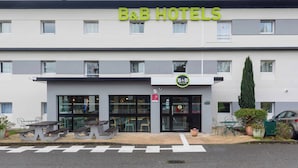A B&B hotel with a modern facade, large windows, and outdoor seating area. - B&B HOTEL Toulouse Cité de l'Espace Hurel (Toulouse)