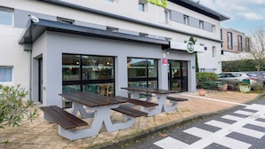 A B&B hotel with a modern facade, outdoor seating, and a clear view of the street. - B&B HOTEL Toulouse Cité de l'Espace Hurel (Toulouse)