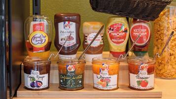 Une sélection de différentes confitures et conserves, notamment de la confiture de figues, de la compote de figues, de la marmelade de figues, des figues séchées et de la confiture de fraises.