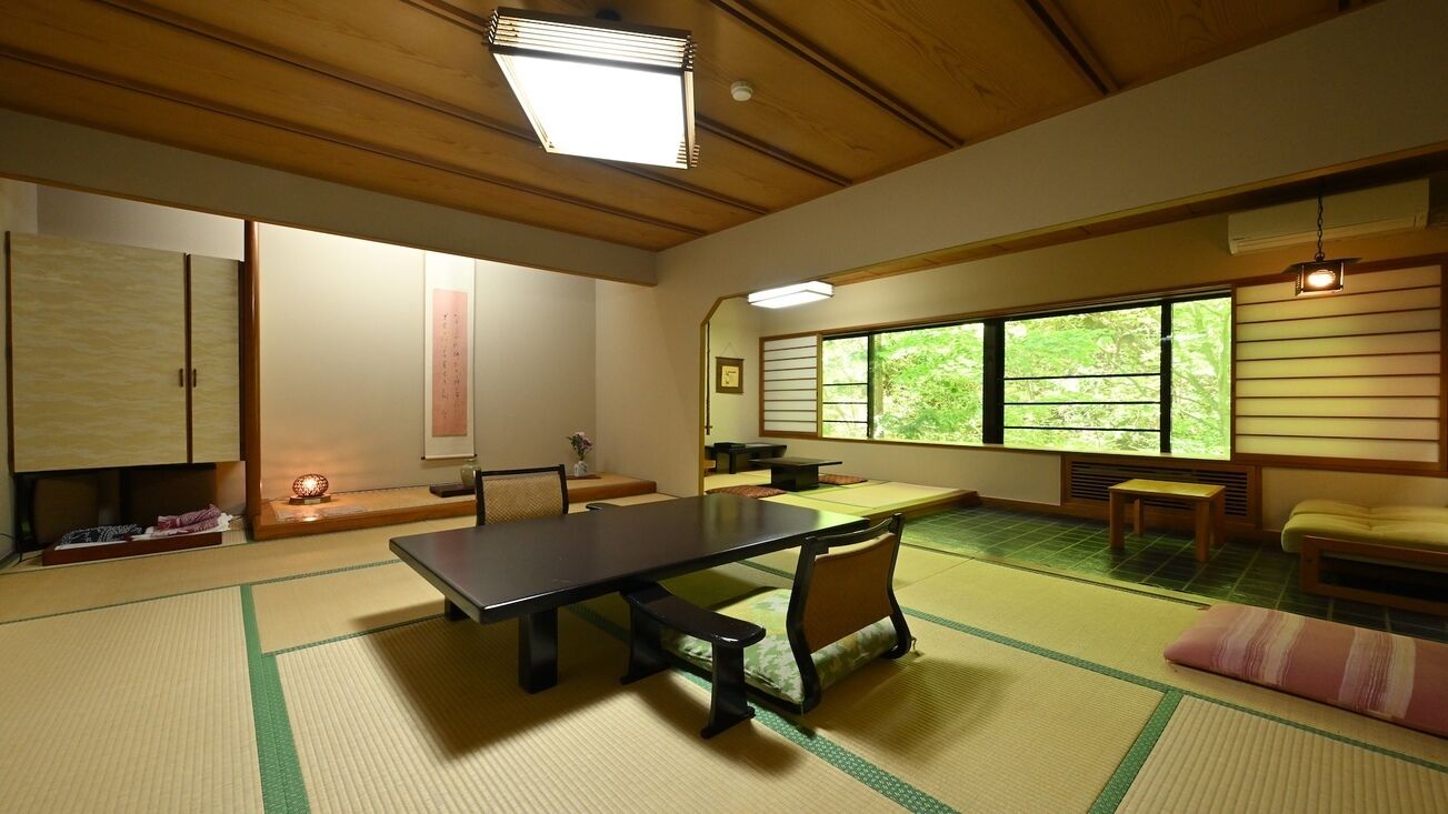 Een kamer met tatami matten, een lage tafel, stoelen en een schuifdeur.