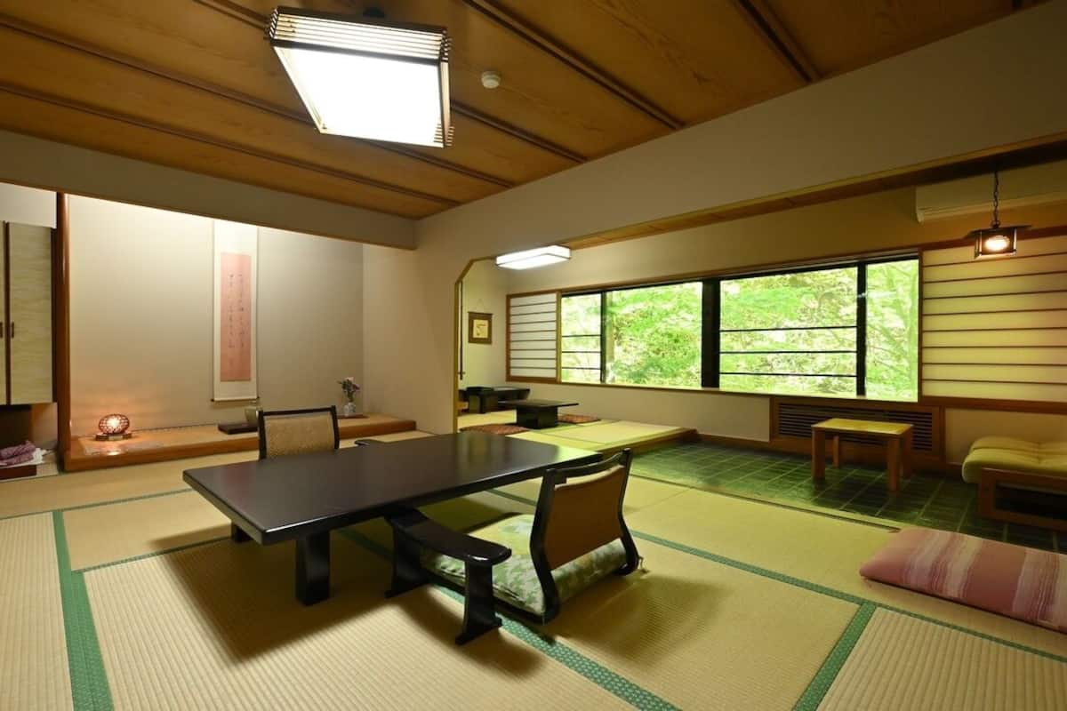 A tatami mat room with a low table, chairs, and a sliding door.
