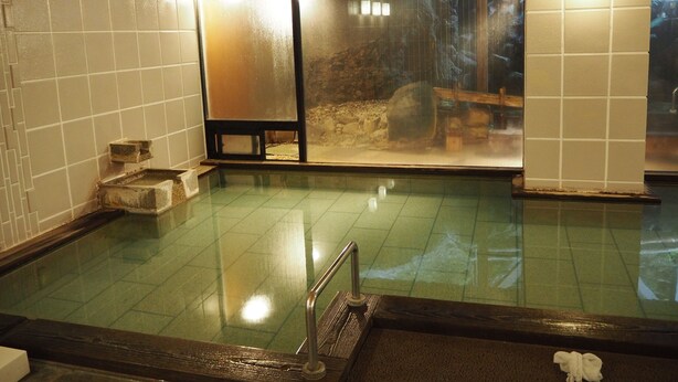 Un onsen japonés tradicional con un banco de madera y una plataforma de piedra.