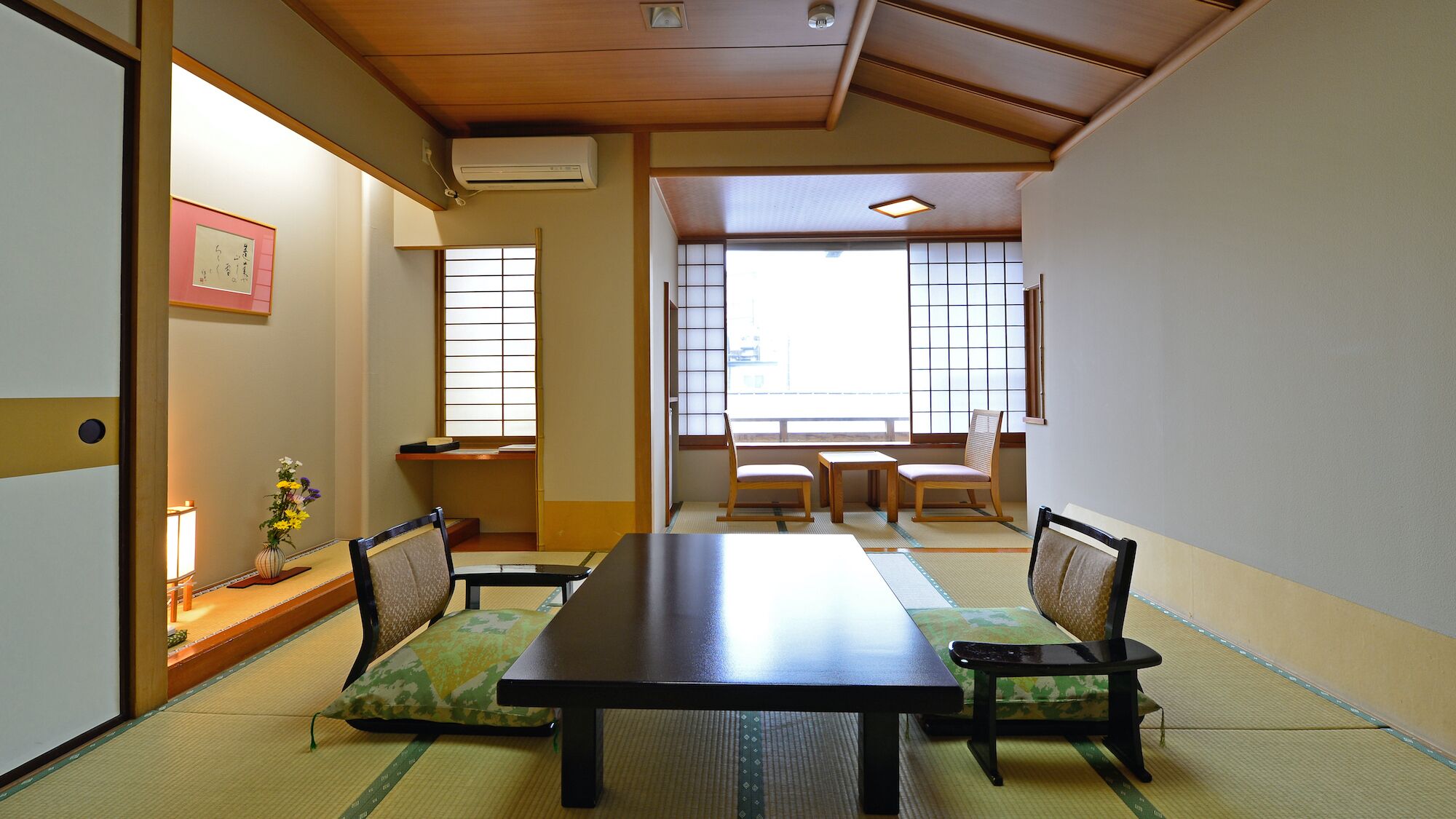 Una habitación japonesa tradicional con suelo de tatami, una mesa baja y puertas correderas.