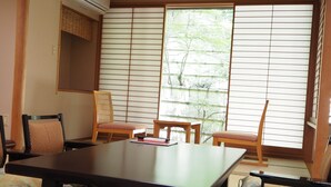 Una habitación japonesa tradicional con esteras de tatami, una mesa baja y dos sillas.