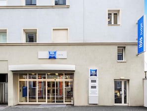 A hotel entrance with a glass door, a digital display for room rates, and a sign indicating the hotel name and location. - ibis budget Graz City (Graz)