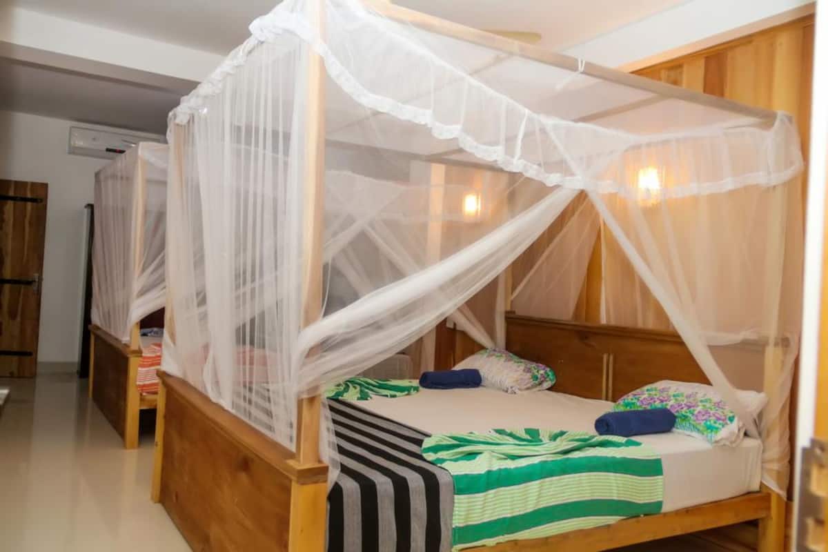 A single wooden bed with a canopy, a bedside table, and a chair.