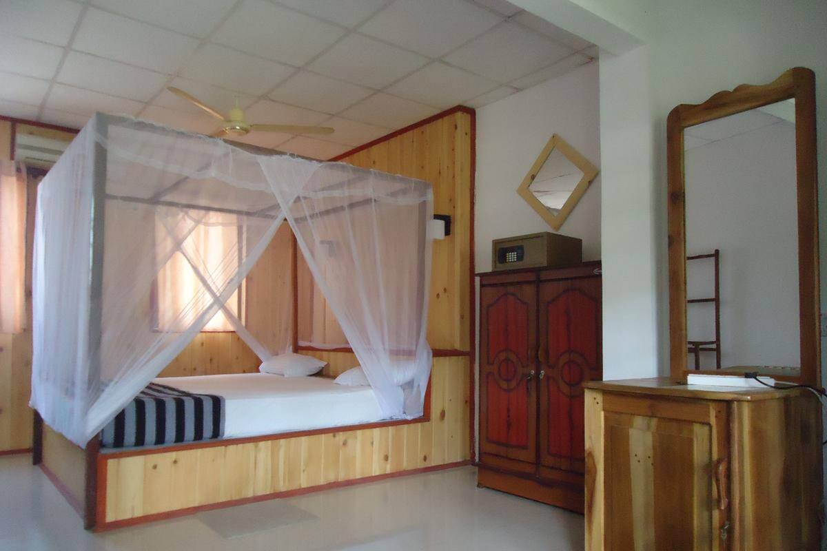 A bedroom with a canopy bed, wooden wardrobe, and a mirror.