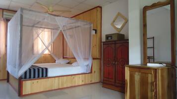 Un dormitorio con cama con dosel, armario de madera y espejo.
