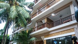 A multi-story building with a restaurant on the second floor, surrounded by palm trees.