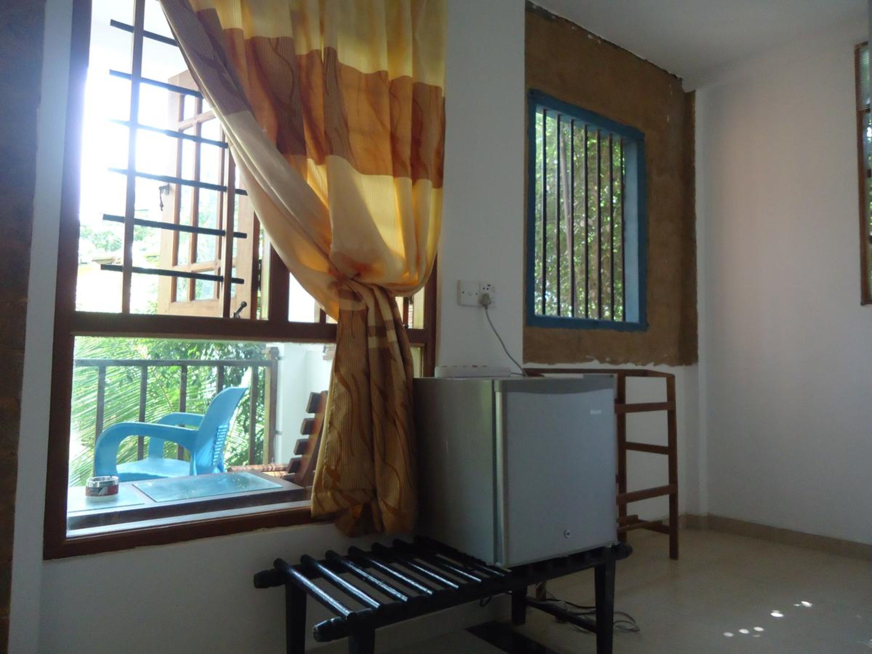 A room with a window, a desk with a chair, and a small refrigerator.