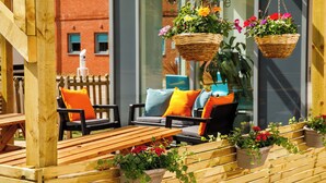 Un espace extérieur aménagé avec du mobilier en bois et des suspensions florales.