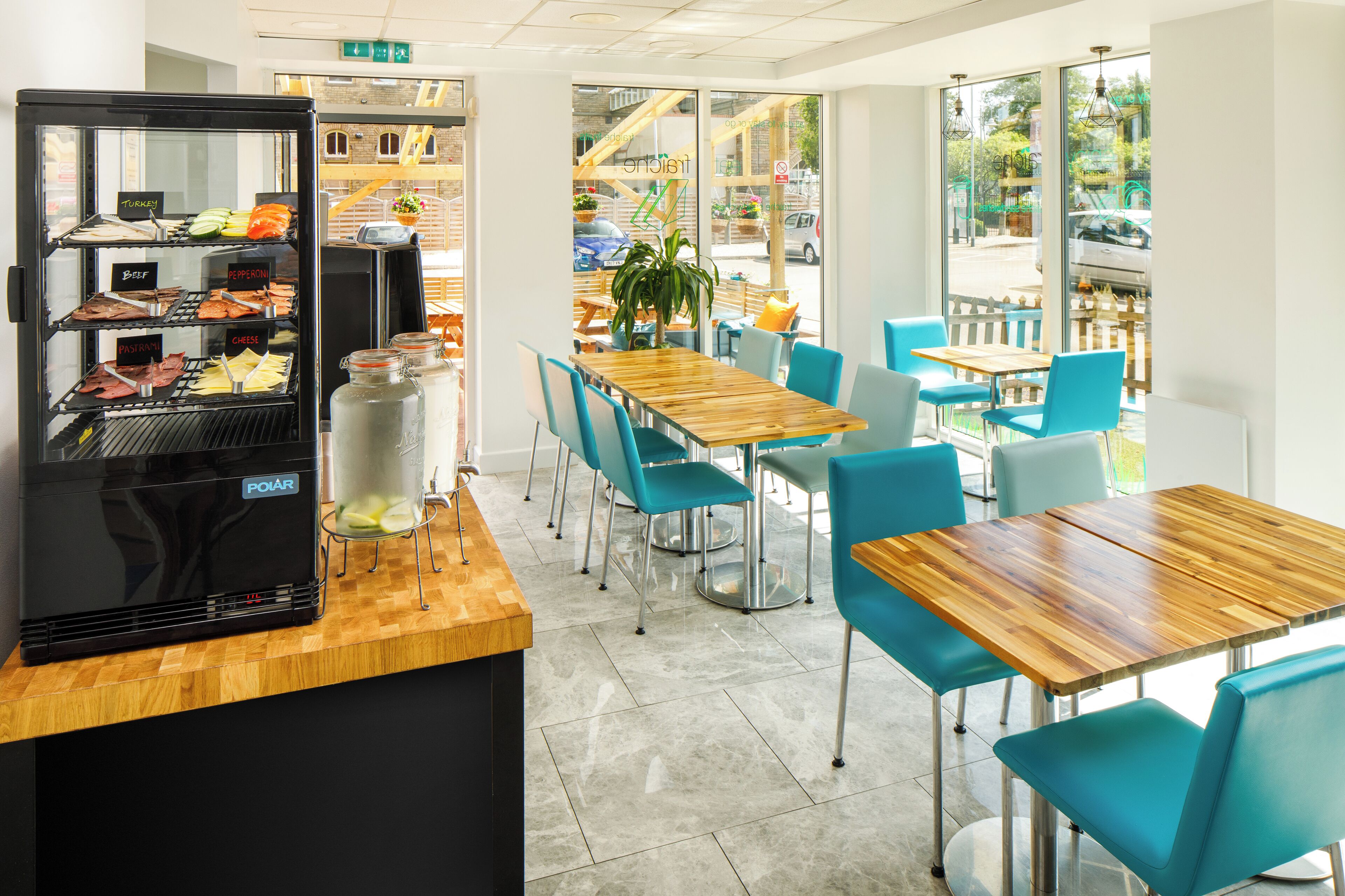 A restaurant with a grill station, blue chairs, and a wooden table.