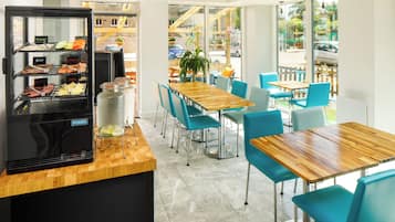 Un restaurante con estación de parrilla, sillas azules y una mesa de madera.