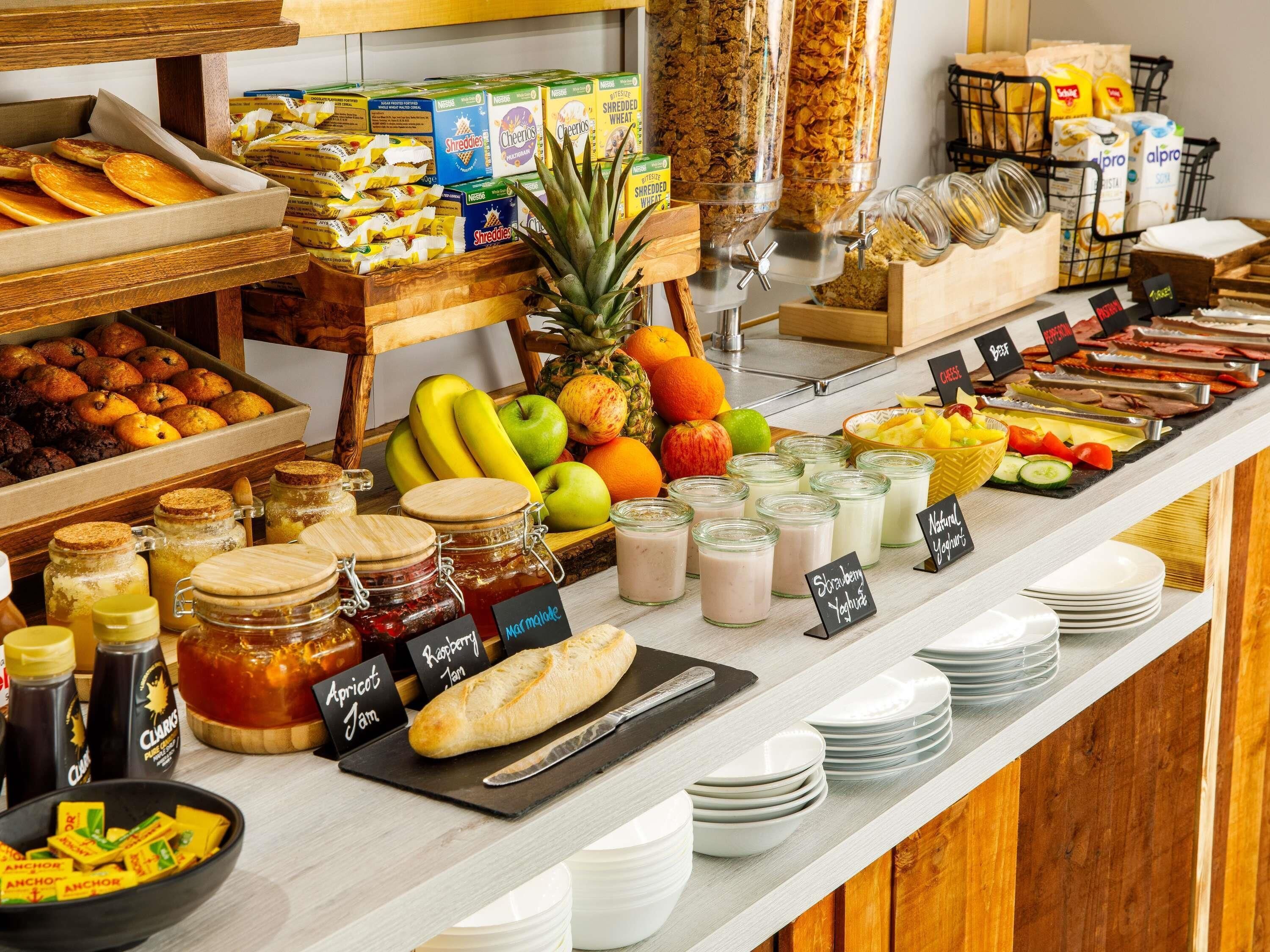 A buffet with various food items including fruits, cereals, and condiments.