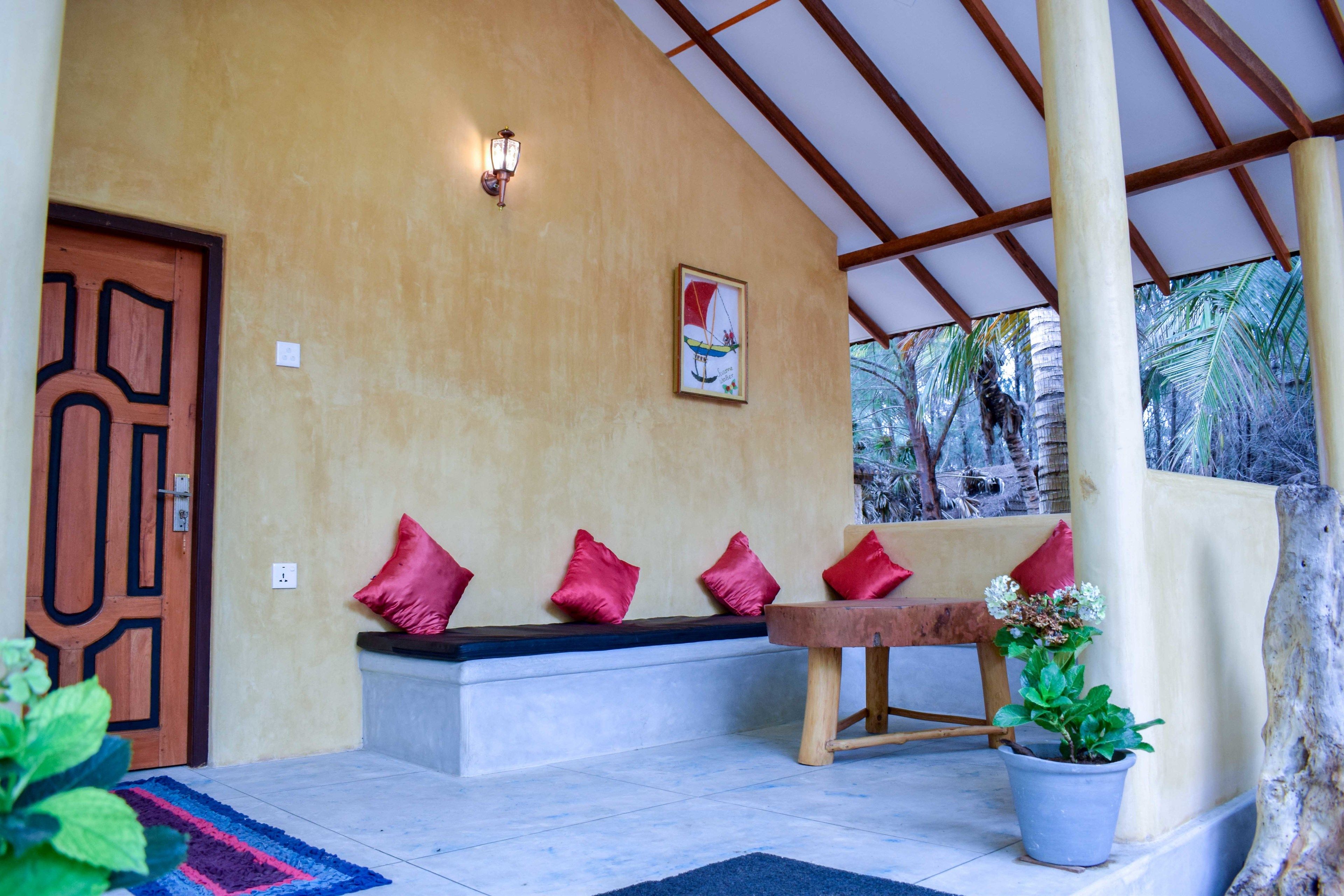 A covered porch with a bench, a wooden door, and a potted plant.