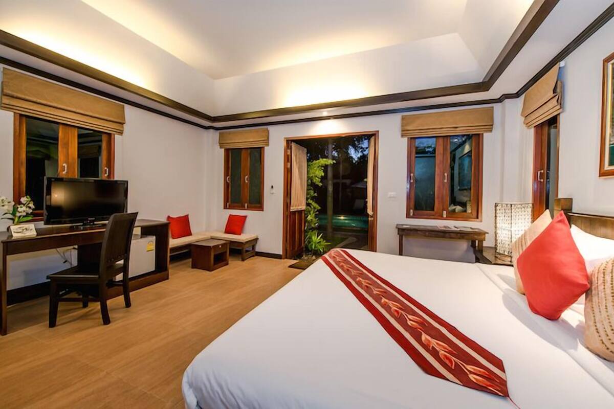 Ein Hotelzimmer mit Bett, Schreibtisch, Fernseher und Blick ins Freie.