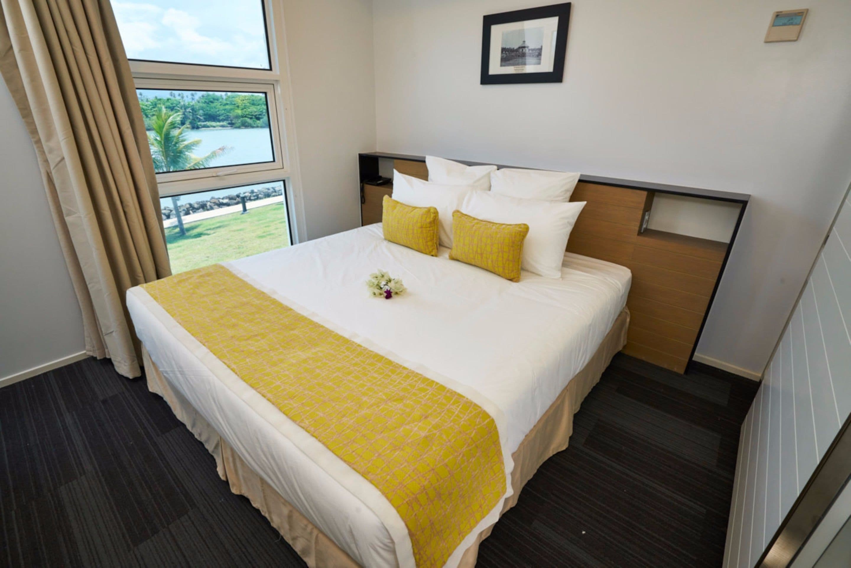 A hotel room with a large bed, a view of a lake, and a framed picture on the wall.
